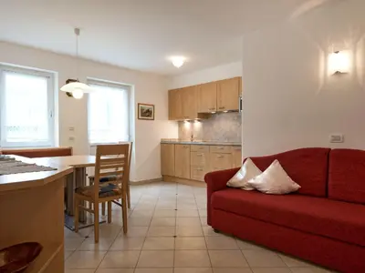 a living room with a red couch and a kitchen at Apartment Ornella-1 by Interhome in Santa Cristina in Val Gardena