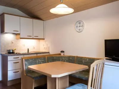a kitchen with a table and a clock on the wall at Apartment Ornella-2 by Interhome in Santa Cristina in Val Gardena