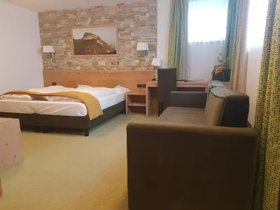 a bedroom with two beds and a desk and a chair at Ciasa Alpina Relax Hotel in Moena
