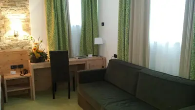 a living room with a couch and a desk at Ciasa Alpina Relax Hotel in Moena