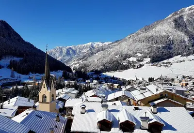 a small town with snow covered roofs and a church at Ciasa Alpina Relax Hotel in Moena