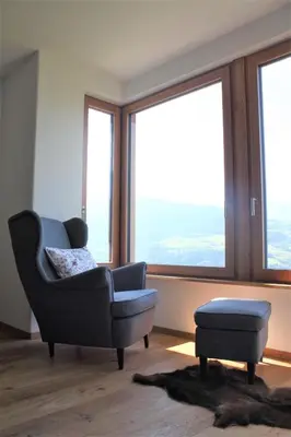 a living room with a chair and a stool and windows at Tschott Hof in Villandro