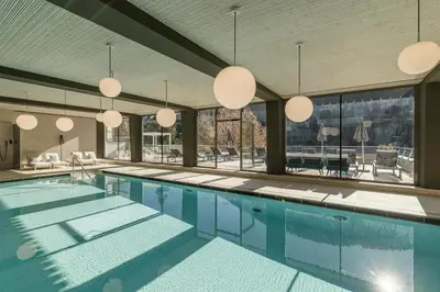 a large swimming pool with large windows and pendant lights at Engel Gourmet&Spa in Nova Levante