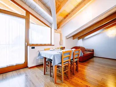 a kitchen with a table and some wooden cabinets at Apartment Belfiore-1 by Interhome in Ronzone
