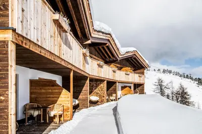 a table with a white plate and forks and wine glasses at Chalet Stern in Vipiteno