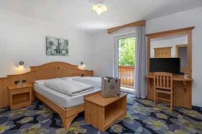 a bedroom with a bed and a desk and a television at Hotel Tirol- Natural Idyll in Montesover