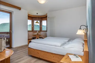 a bedroom with a bed and a table and windows at Hotel Tirol- Natural Idyll in Montesover