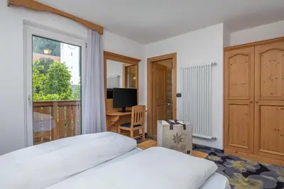 a bedroom with a bed and a window and a desk at Hotel Tirol- Natural Idyll in Montesover