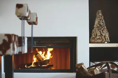 a fireplace with a fire in it and a christmas tree at Lagació Hotel Mountain Residence in San Cassiano