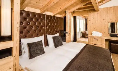 a bedroom with a large bed with a wooden wall at Lagació Hotel Mountain Residence in San Cassiano