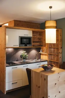 a kitchen with white cabinets and a wooden table at Lagació Hotel Mountain Residence in San Cassiano