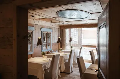 a dining room with white tables and chairs at Lagació Hotel Mountain Residence in San Cassiano