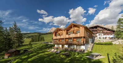 a large wooden house on a grassy hill at Hotel Rezia in La Villa