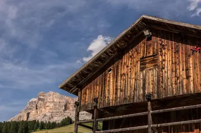 a wooden barn with a mountain in the background at Hotel Rezia in La Villa
