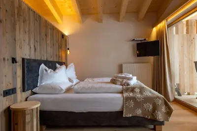 a bedroom with a bed with white sheets and pillows at Hotel Rezia in La Villa
