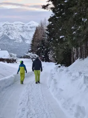 two people walking down a snow covered road at Hotel Vienna in San Martino di Castrozza