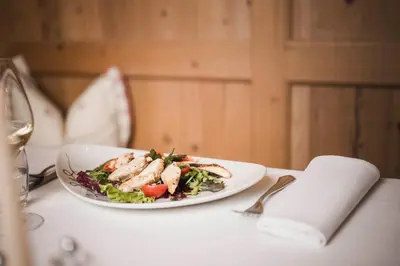 a plate of chicken salad on a table with a napkin at Hotel Ansitz Jakoberhof in Ortisei