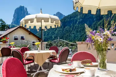 a patio with tables and chairs with food and flowers at Hotel Ansitz Jakoberhof in Ortisei