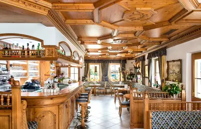 a restaurant with wooden ceilings and tables and chairs at Hotel Ansitz Jakoberhof in Ortisei