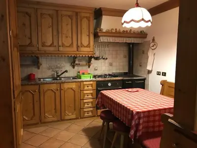 a kitchen with wooden cabinets and a table with a table cloth at Sweet Home in Cortina dʼAmpezzo