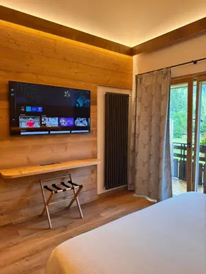 a bedroom with a flat screen tv on a wall at Albergo Scoiattolo in Falcade