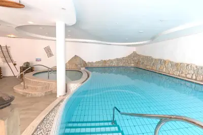 a large swimming pool with a tub in a building at Pineta Natural Chalet in Coredo