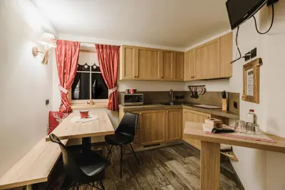 a kitchen with wooden cabinets and a table and chairs at Majon de la nona in Pozza di Fassa