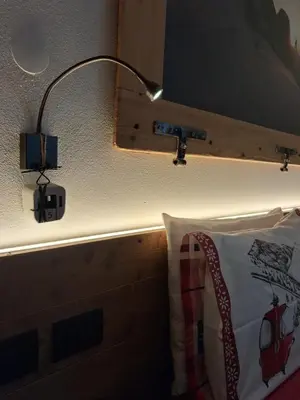 a lamp on a wall next to a bed at Majon de la nona in Pozza di Fassa