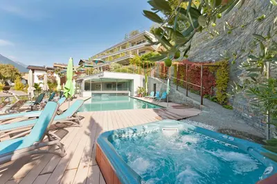 a swimming pool with chairs and a building at Christophs Hotel in Schenna