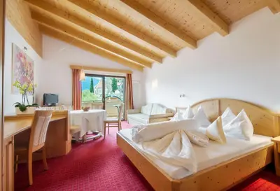 a hotel room with a bed and a dining room at Christophs Hotel in Schenna