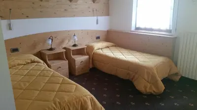 a bedroom with two beds and a window and two lamps at Hotel El Mondin in Fiera di Primiero