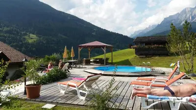 a resort with a swimming pool and mountains in the background at Hotel El Mondin in Fiera di Primiero