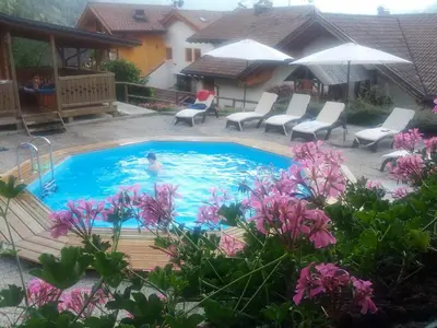 a swimming pool with chairs and a person in the water at Hotel El Mondin in Fiera di Primiero