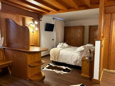 a bedroom with a bed with wooden walls and wooden floors at Hotel El Mondin in Fiera di Primiero
