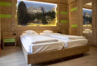 two beds in a wooden room with a large window at Berg Hotel Latemar Spitze in Vigo di Fassa