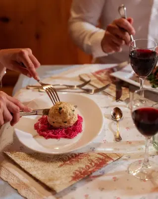 a plate of food on a table with two people eating at Berg Hotel Latemar Spitze in Vigo di Fassa