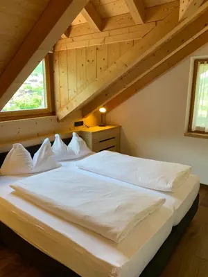 a bedroom with a large white bed in a attic at Villa sulla passeggiata in Ortisei