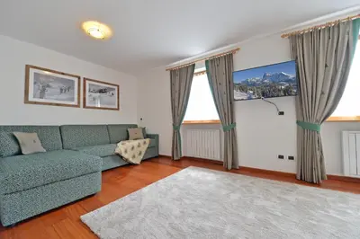 a living room with a green couch and two windows at Villa sulla passeggiata in Ortisei