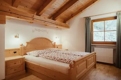 a bedroom with a wooden bed and a window at Ciasa Pedaga in San Vigilio Di Marebbe