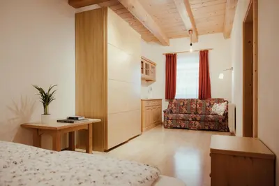 a bedroom with a bed and a chair and a table at Ciasa Pedaga in San Vigilio Di Marebbe