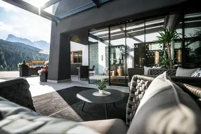 a house with a lawn with a chair in the yard at Hotel La Fradora - Dolomites Hotel in San Cassiano