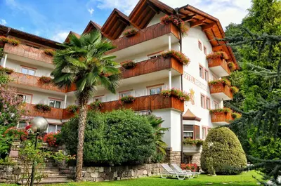 a building with a palm tree in front of it at Hotel Brunner in Merano
