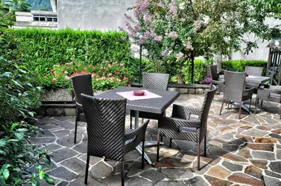 a patio with a table and chairs on a stone patio at Hotel Brunner in Merano