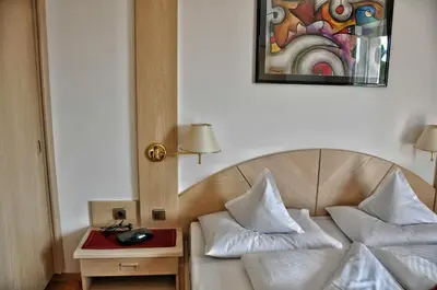 a hotel room with a bed with a phone on a table at Hotel Brunner in Merano