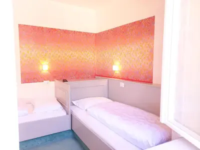 a small room with two beds and a window at Hotel Schuster in Colle Isarco