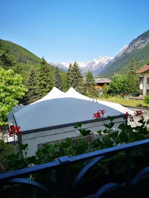 a large white tent in a yard with mountains at Hotel Schuster in Colle Isarco