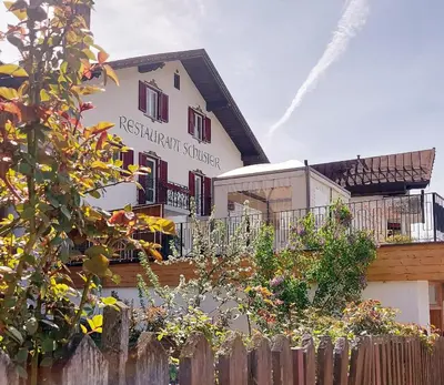 a white building with a fence in front of it at Hotel Schuster in Colle Isarco