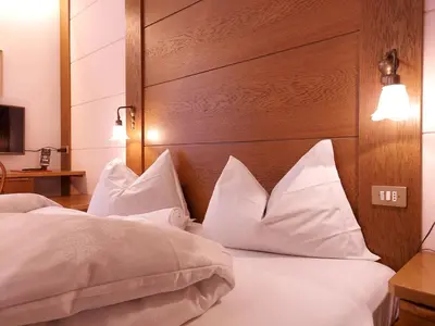 a hotel room with two beds with white pillows at Hotel Schuster in Colle Isarco