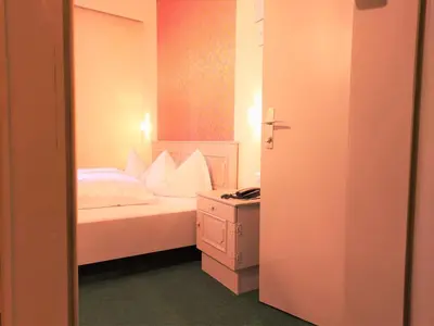 a bedroom with a bed with white sheets and pillows at Hotel Schuster in Colle Isarco