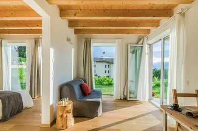 a bedroom with a bed and a chair and sliding glass doors at B&B Lupo in Cavareno